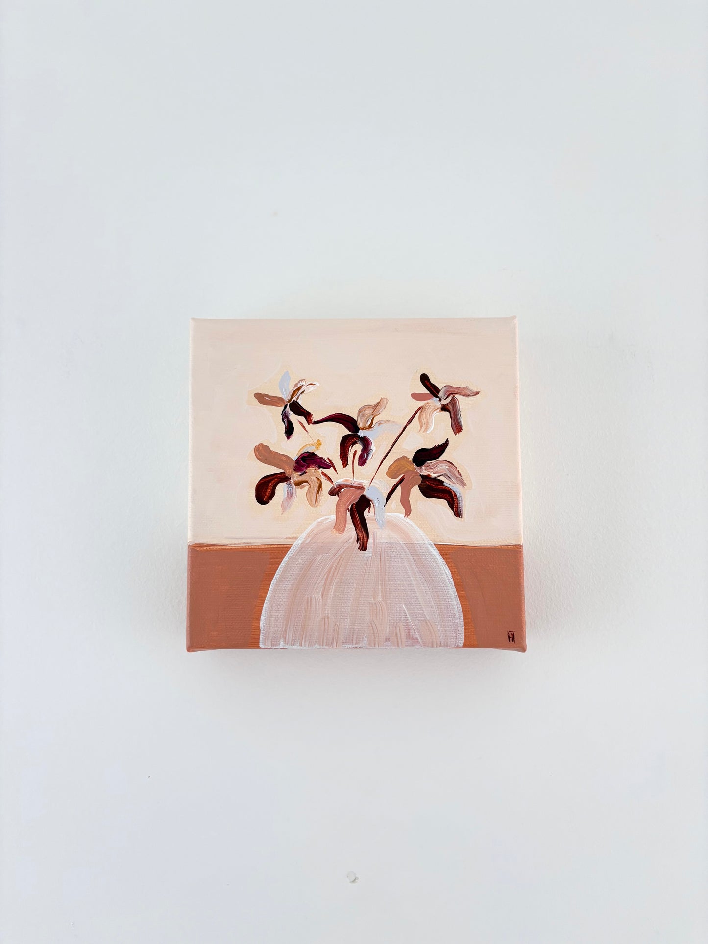 Brown and pink abstract flower arrangement in a white vase with a split burnt orange and cream background.