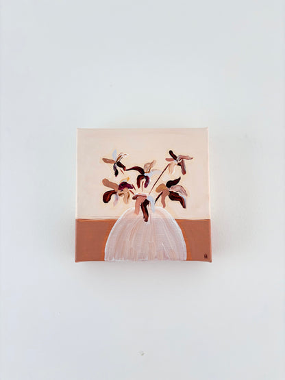 Brown and pink abstract flower arrangement in a white vase with a split burnt orange and cream background.
