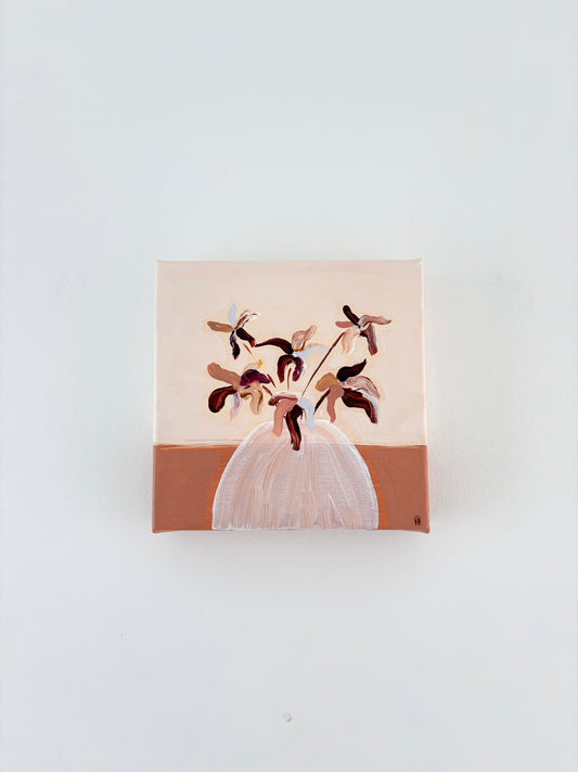 Brown and pink abstract flower arrangement in a white vase with a split burnt orange and cream background.