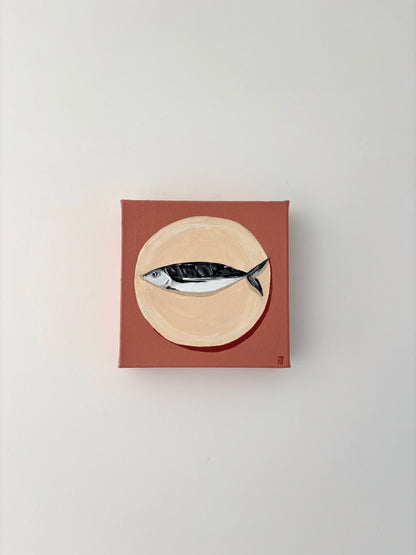Painting of a fish on a beige circle plate with a dusty pink background.