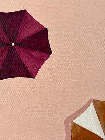 Framed artwork with Ariel view of burgundy and mustard umbrellas. Peach background. 
