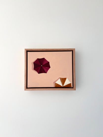 Framed artwork with Ariel view of burgundy and mustard umbrellas. Peach background. 